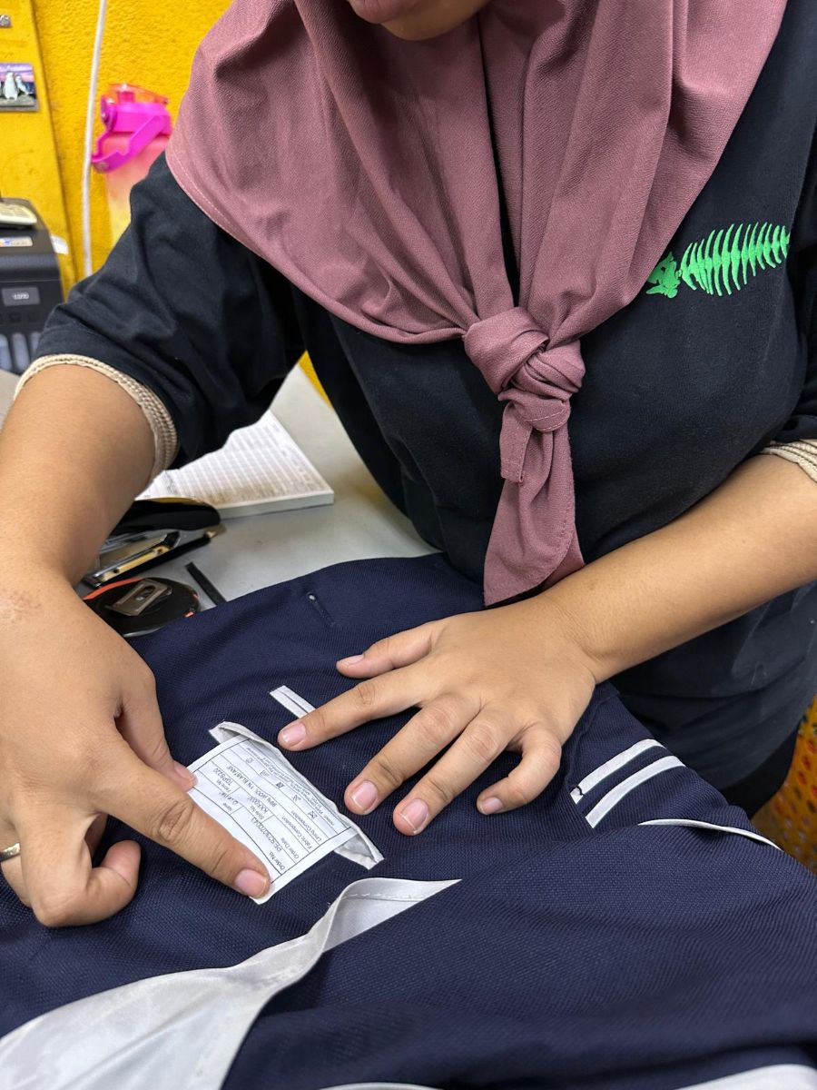 Astoria staff member checking the care label on a navy school blazer by hand